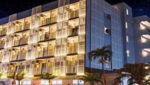 A multi-story hotel with balconies, large windows, and palm trees in the foreground. - The BREAKFAST HOTEL PORTO Ishigakijima (Ishigaki)