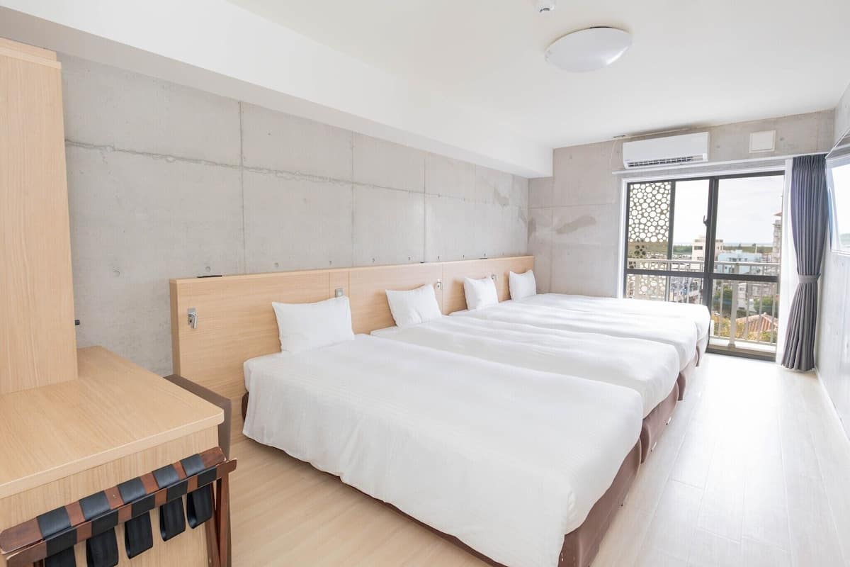 A hotel room with a large bed, a wooden desk, and a balcony with a view.