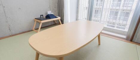 Ein Zimmer mit einem großen Fenster, einem Stehpult und einem kleinen Tisch mit einem Stuhl.