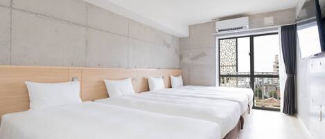 A hotel room with two beds, a large window, and a view of buildings.