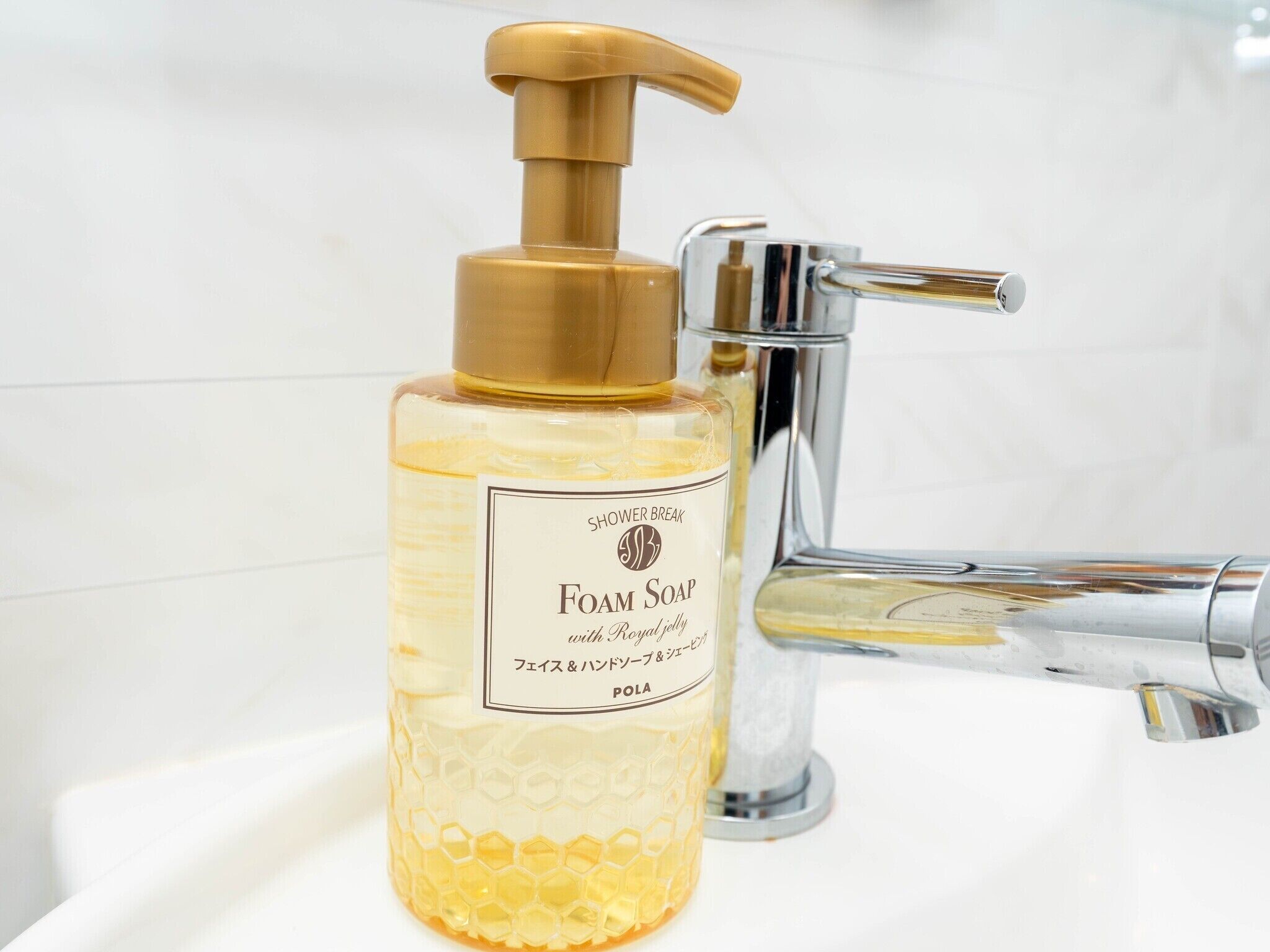 Een badkamer met een douche, schuimzeepdispenser en een chromen kraan.