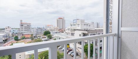 Un balcón con vista a un paisaje urbano, que incluye edificios y coches estacionados.