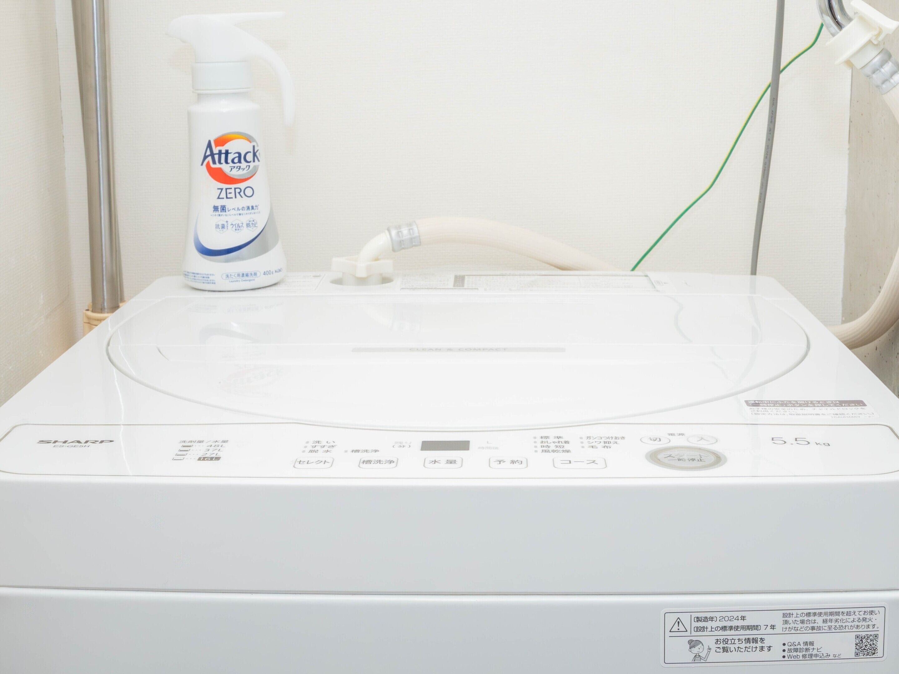 Une machine à laver avec une bouteille de lessive Attack Zero posée sur le dessus.