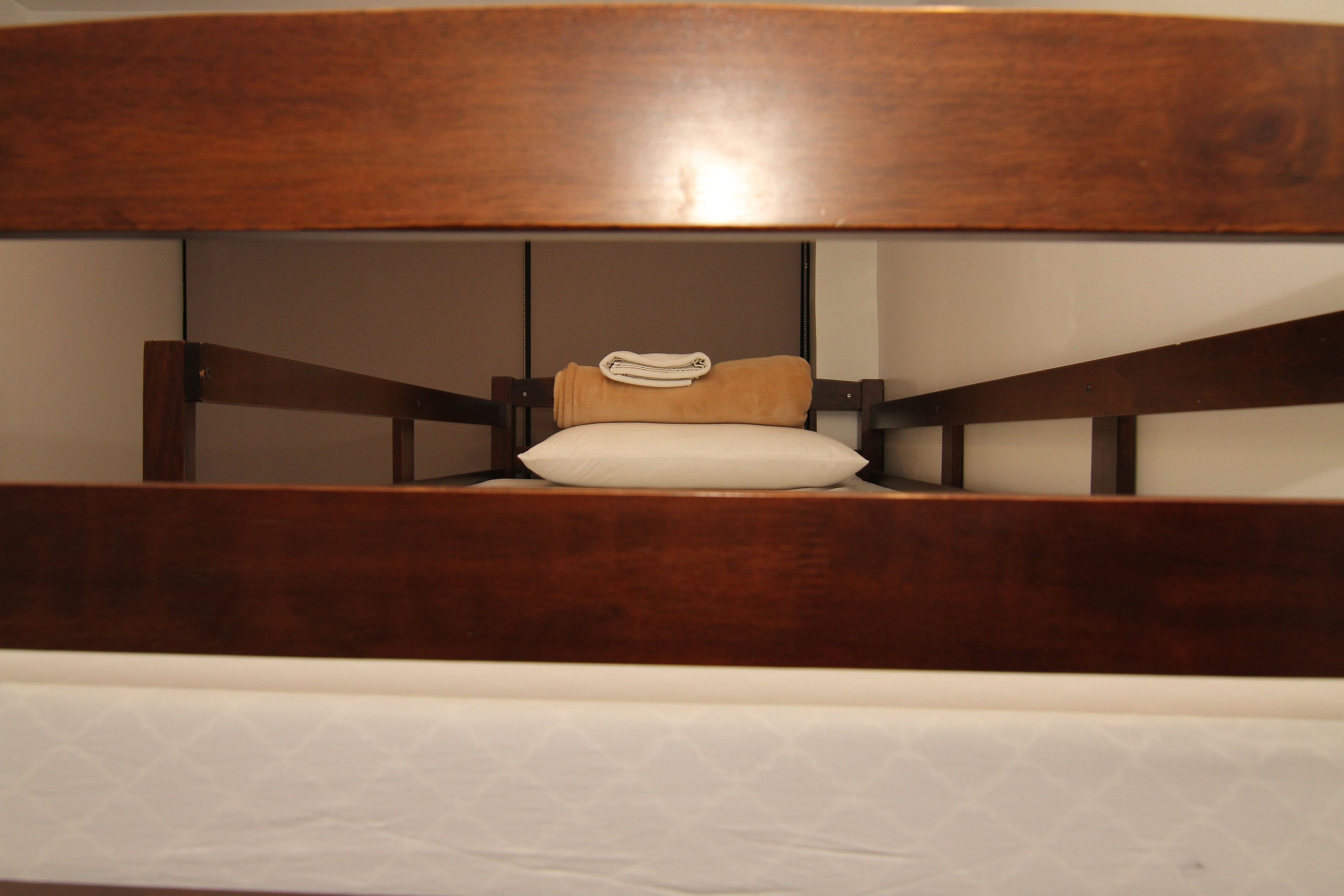 A bed with a wooden headboard and a white mattress.
