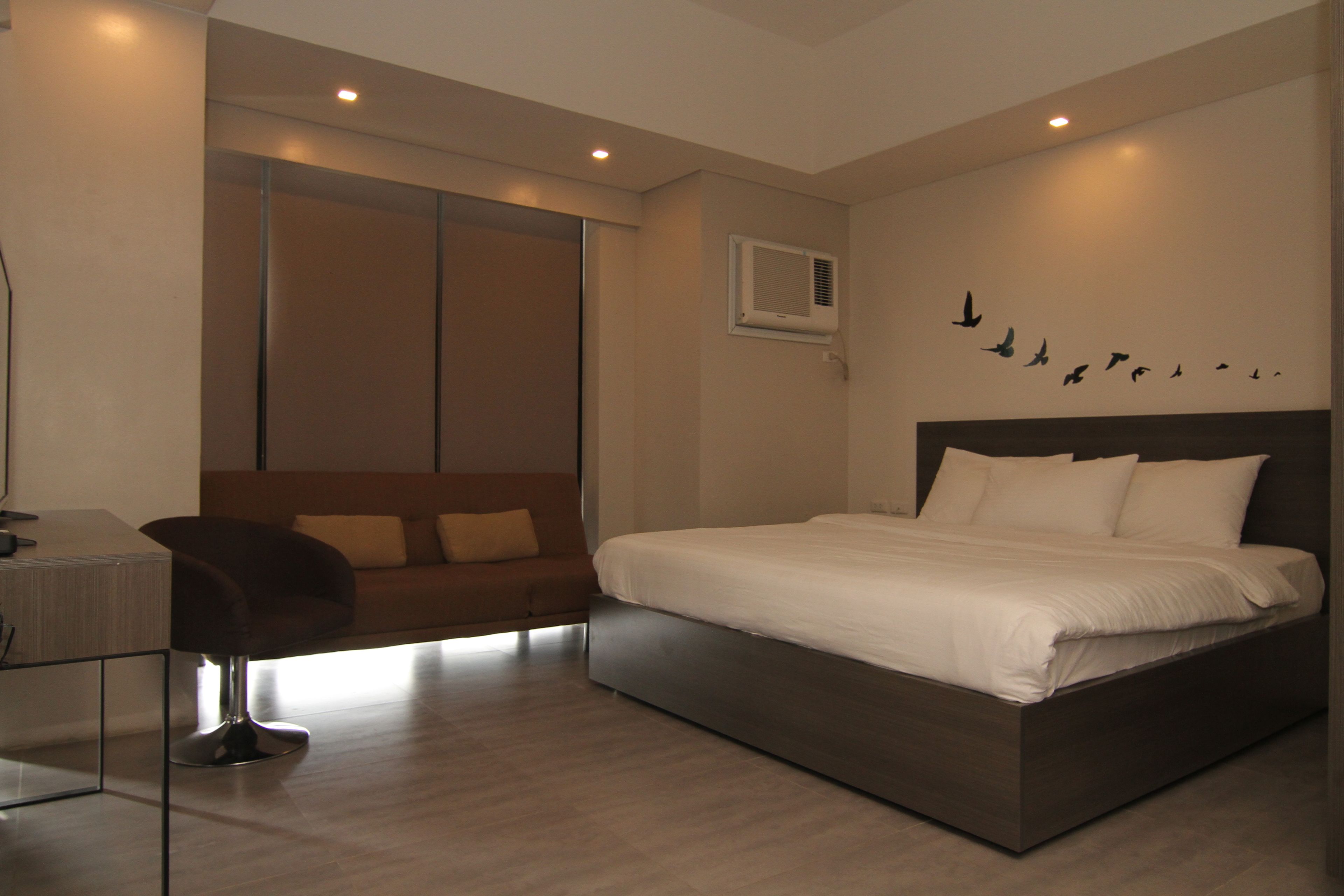 A modern bedroom with a large bed, a desk, and a sofa.