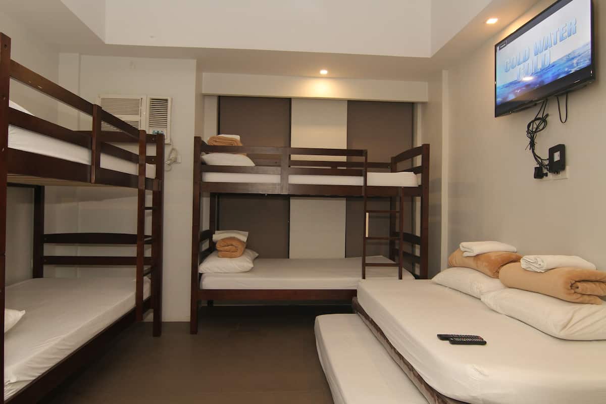 A bunk bed room with a television on the wall.