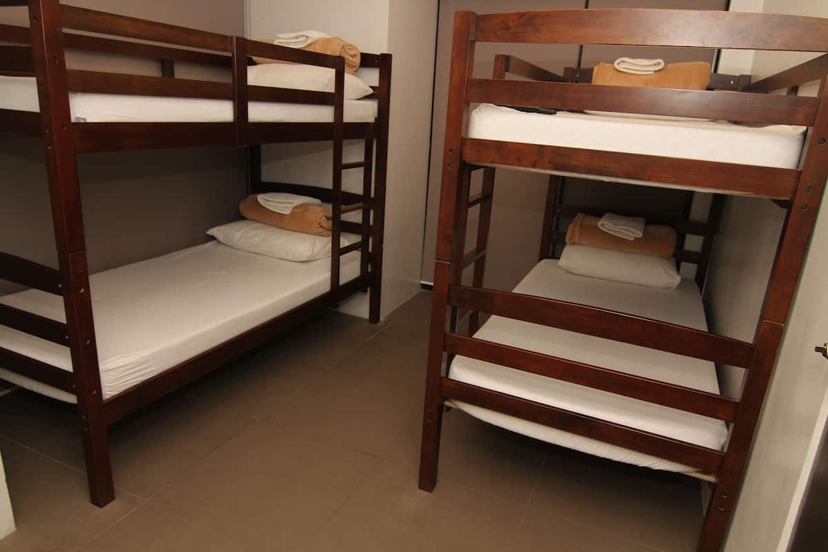 Two wooden bunk beds with white bedding and brown pillows.