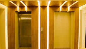 Un ascensor con paneles de madera y diseño moderno, que cuenta con un panel de control con un botón y una pantalla digital.