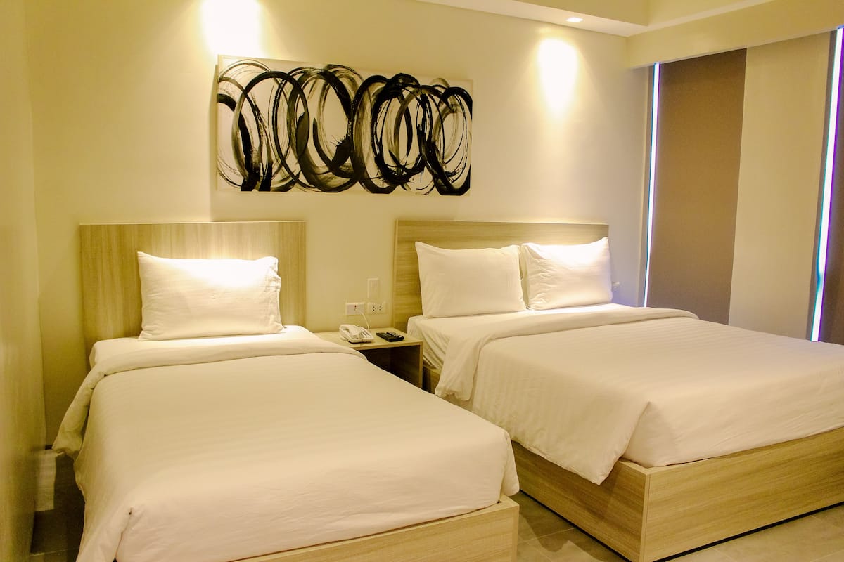 A hotel room with two beds, a modern abstract art piece above the beds, and a nightstand with a phone and lamp.