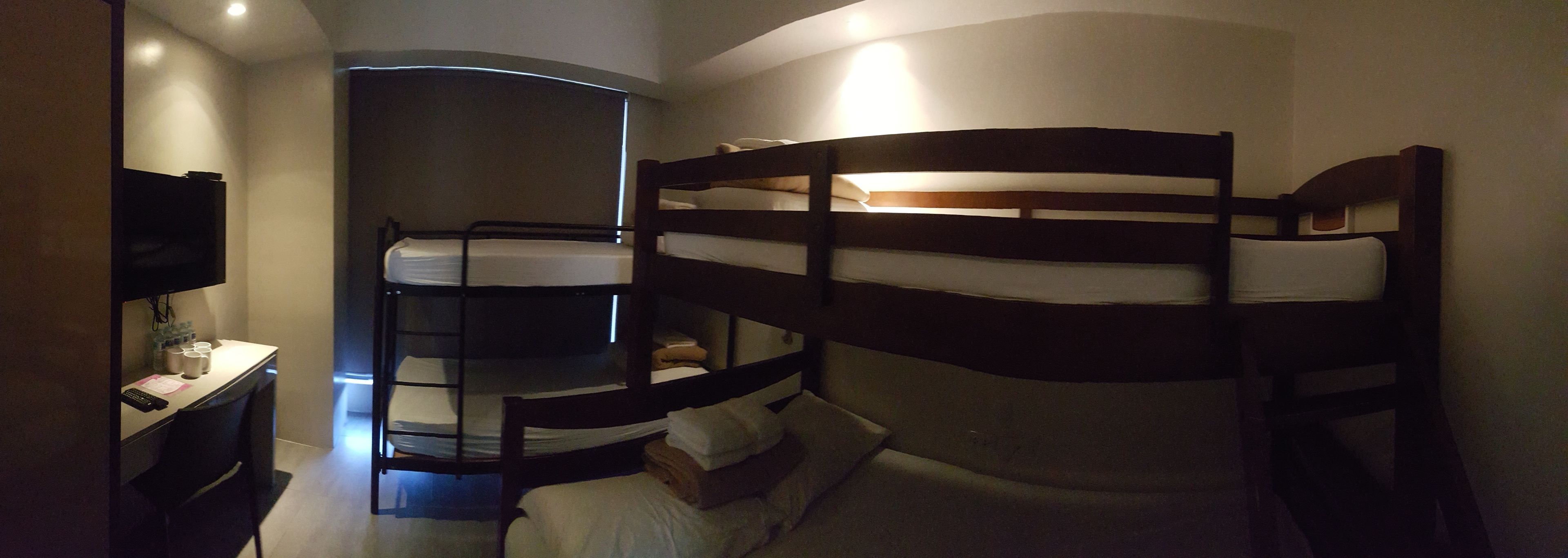 A bunk bed room with a desk and a TV.