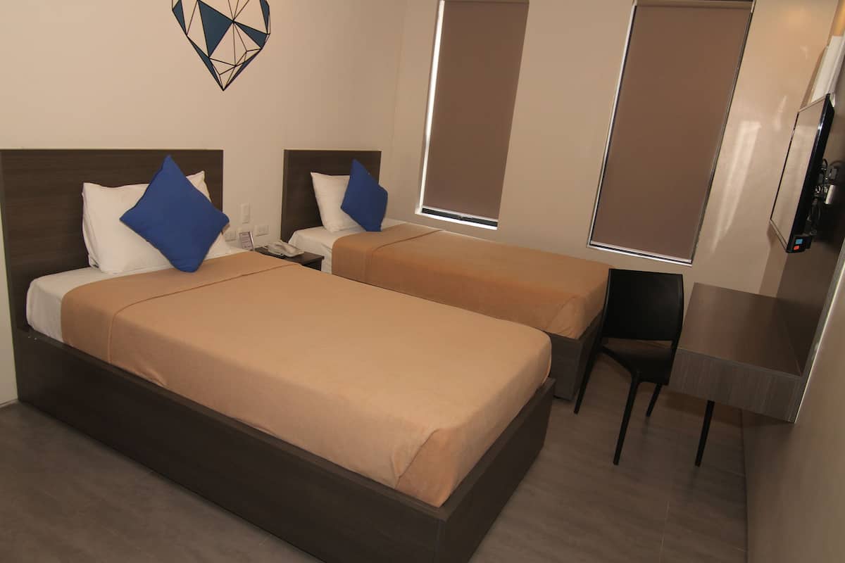 A hotel room with two beds, a desk, and a TV.