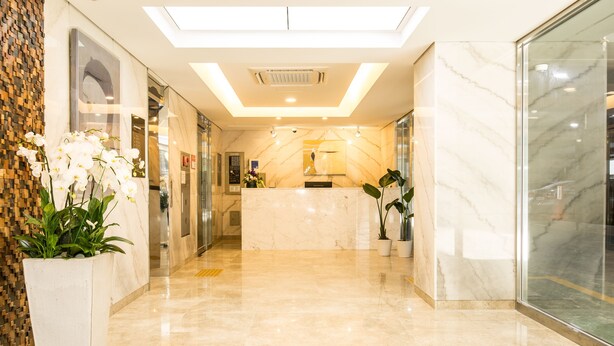 A modern hotel lobby with a marble reception desk, a glass elevator, and potted plants. - Sleep with Your Own Pet Only - The Petel (Busan)