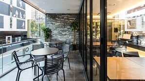 A modern cafe with a glass wall, metal chairs, and a stone wall interior. - Sleep with Your Own Pet Only - The Petel (Busan)