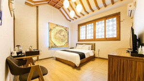 Een hotelkamer met een houten bed, een bureau met stoel, een groot raam met een rasterpatroon en een kaart als kunstwerk aan de muur.