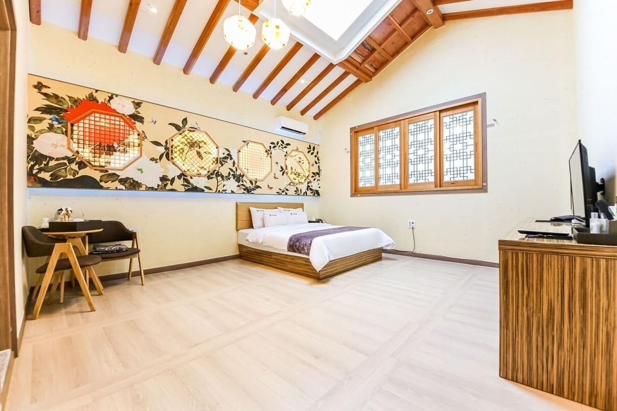 A room with a bed, a desk, a chair, a wooden cabinet, and a large window.