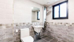 Een badkamer met toilet, wastafel en douche.