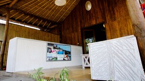 A reception area with a wooden ceiling, a reception desk, and a large poster. - Beach Camp (Gili Trawangan)