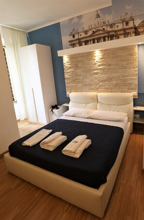 A hotel room with a large bed, a wardrobe, a nightstand, and a wall with a decorative mural. - Rooma beb (Rome)
