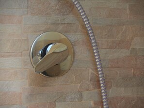A showerhead with a flexible hose against a stone wall. - Rooma beb (Rome)