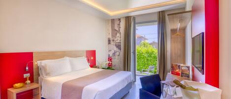 Habitación de hotel moderna con una cama grande, mesita de noche y vistas a zonas verdes.