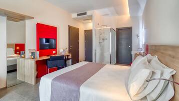 A modern hotel room with a large bed, a desk with a TV, a shower, and a wardrobe.