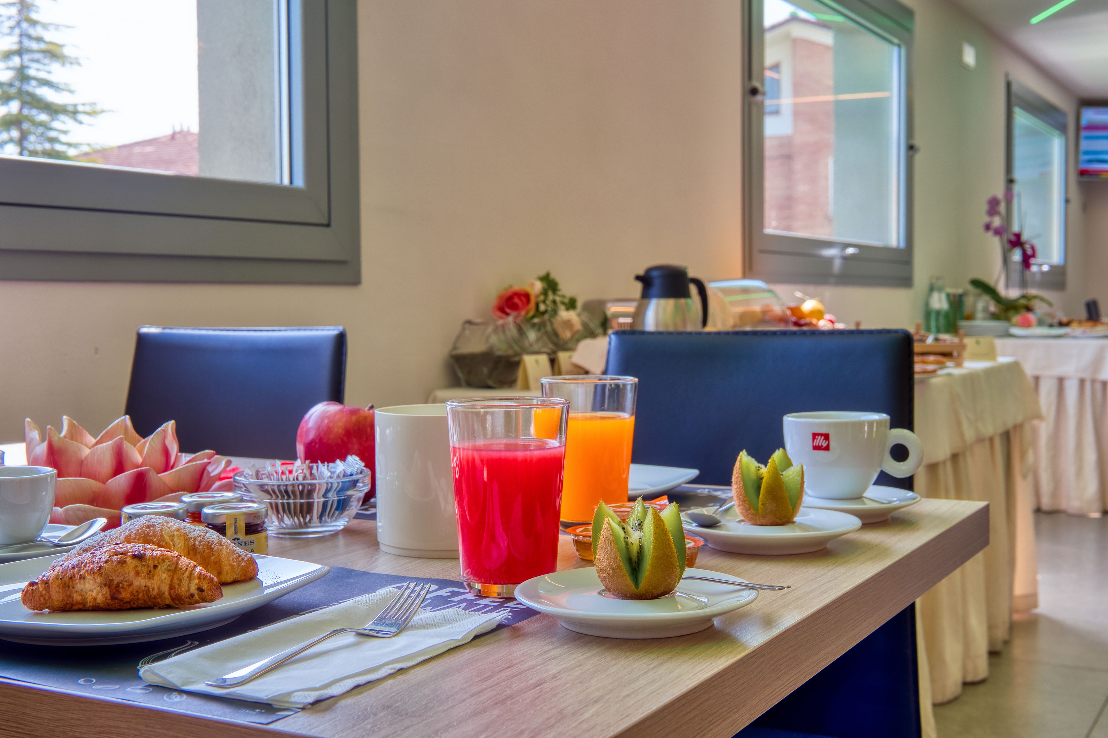 Une table de petit-déjeuner avec des croissants, des fruits, du jus et du café.