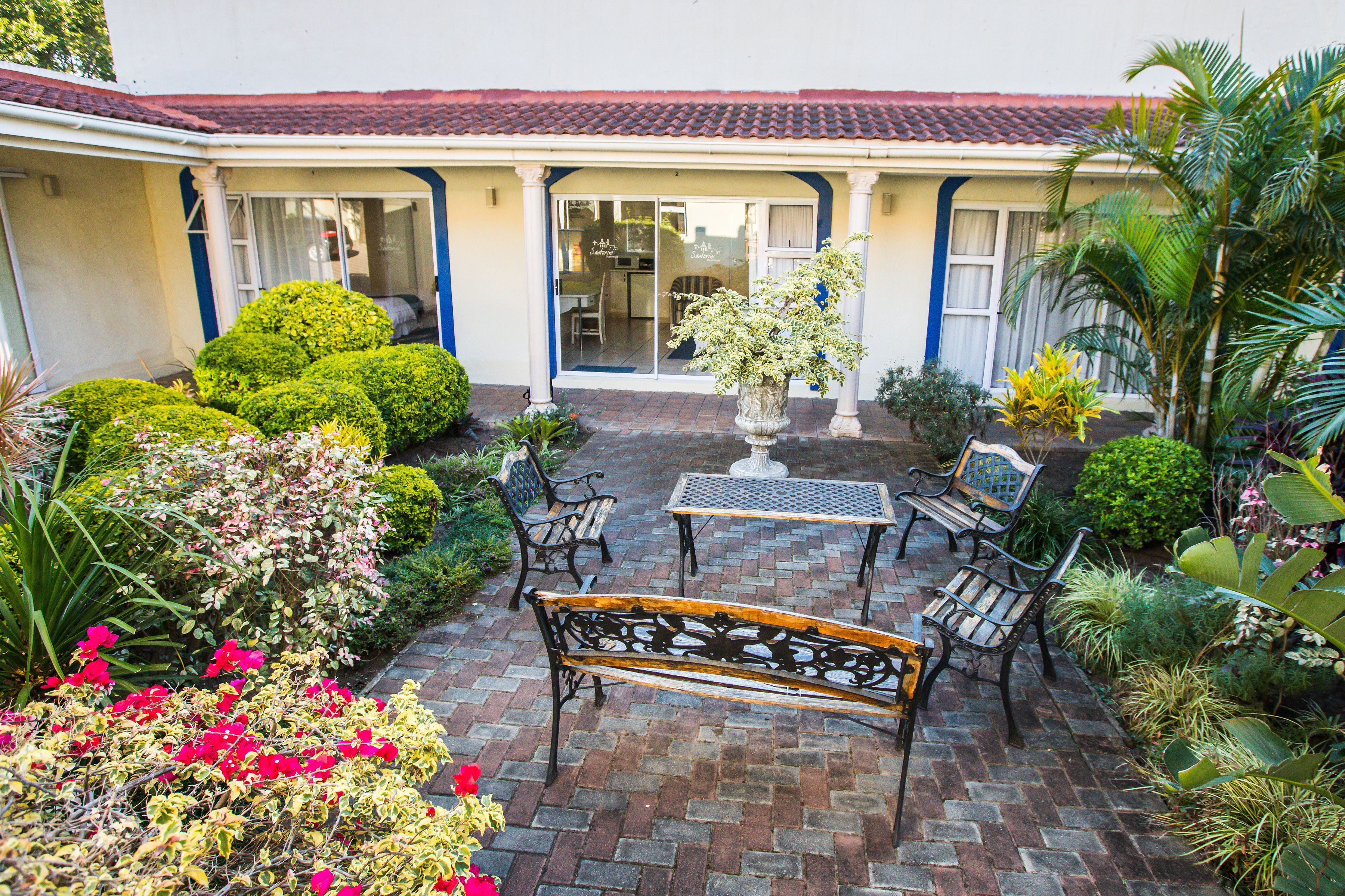 A courtyard with a patio area, including a table, benches, and potted plants.