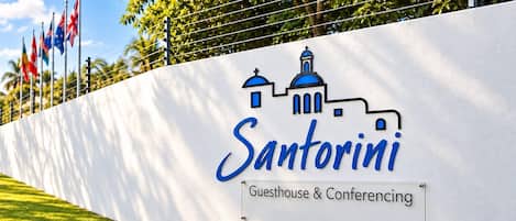 Una pared con un logotipo y texto que indica 'Santorini Guesthouse & Conferencing'.