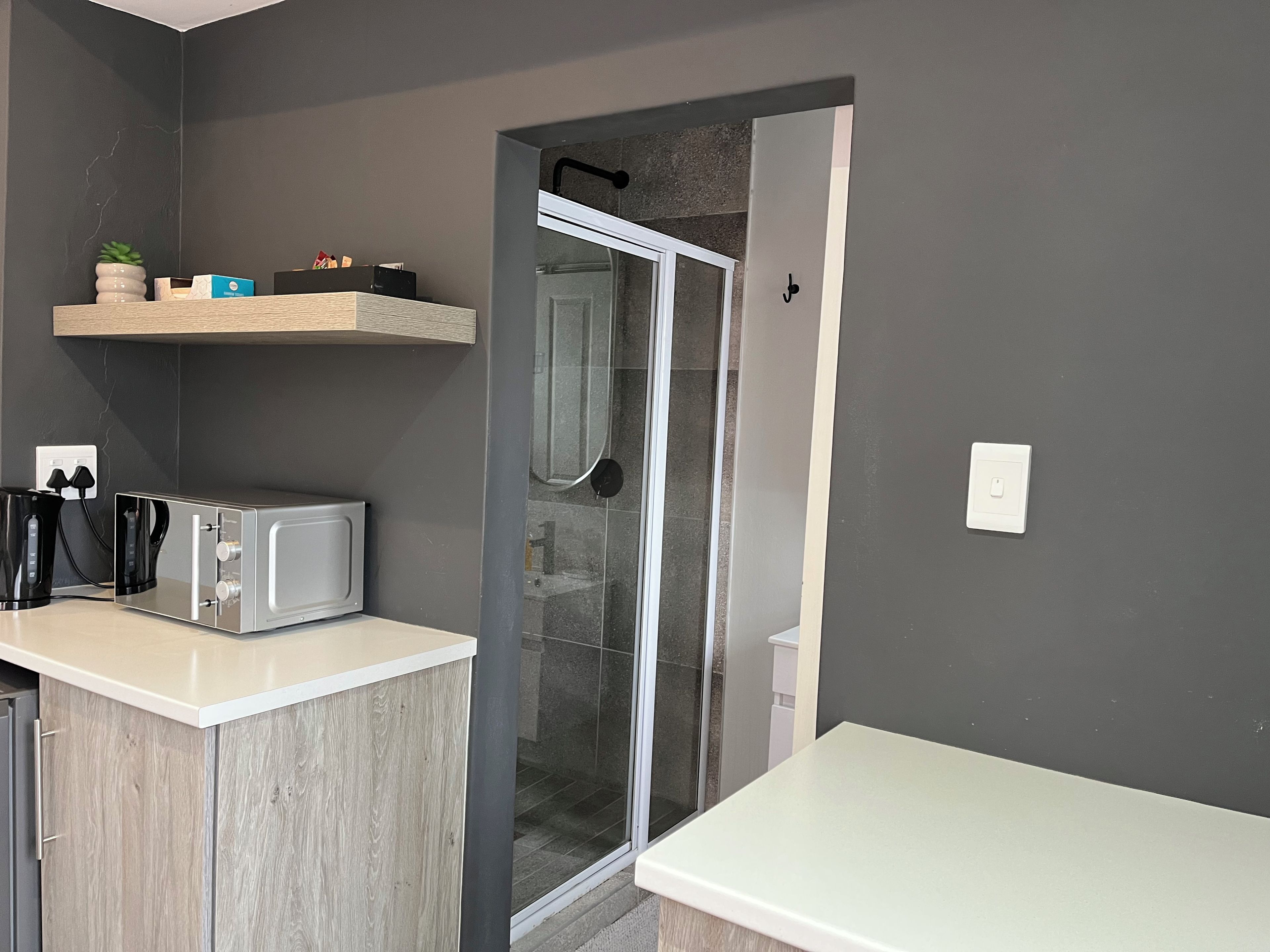 Una cocina moderna con microondas, tostadora y cafetera sobre una encimera blanca.