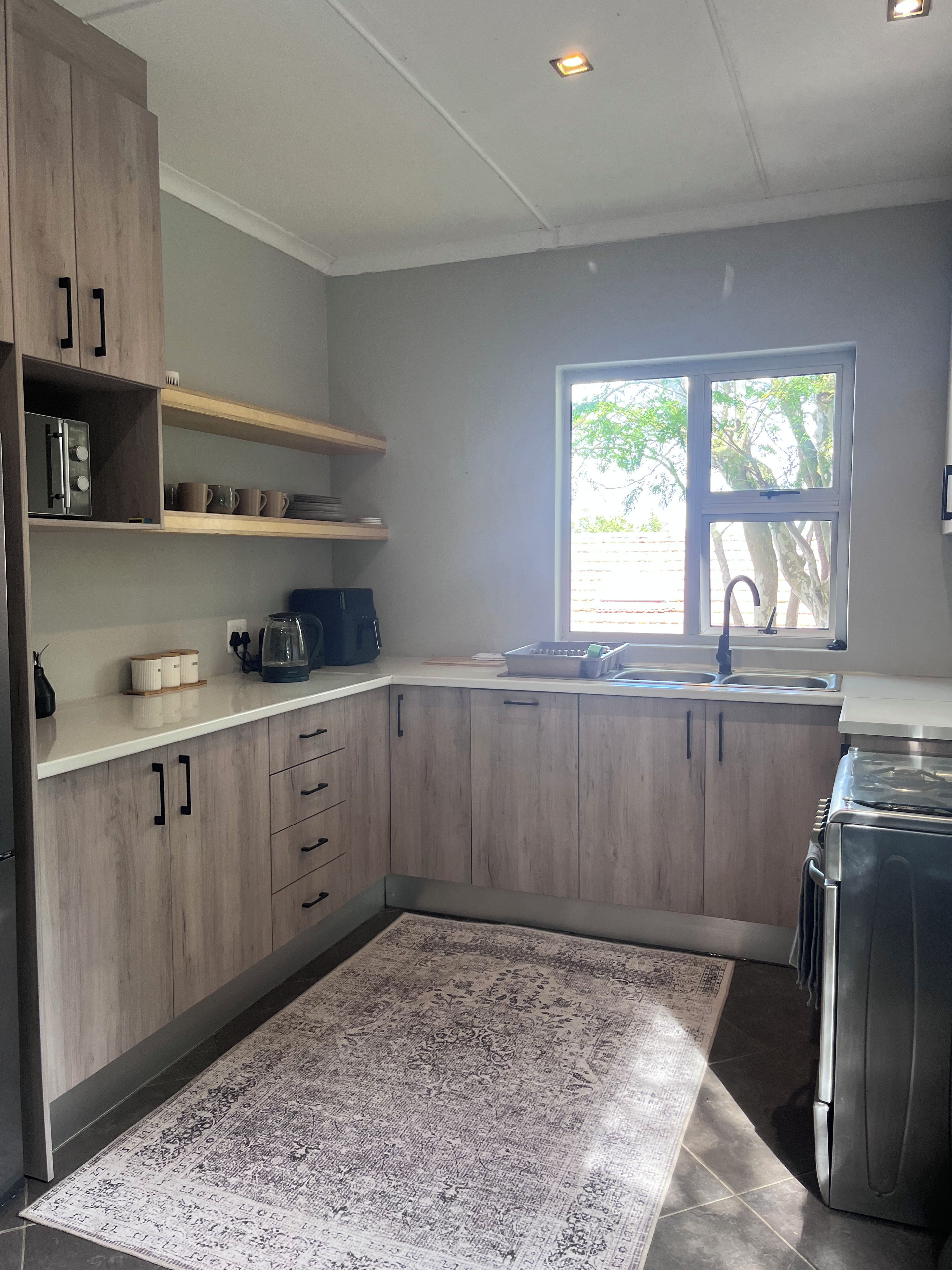 Una cocina moderna con armarios de madera, estufa integrada, un lavabo y un ventanal que proporciona luz natural.