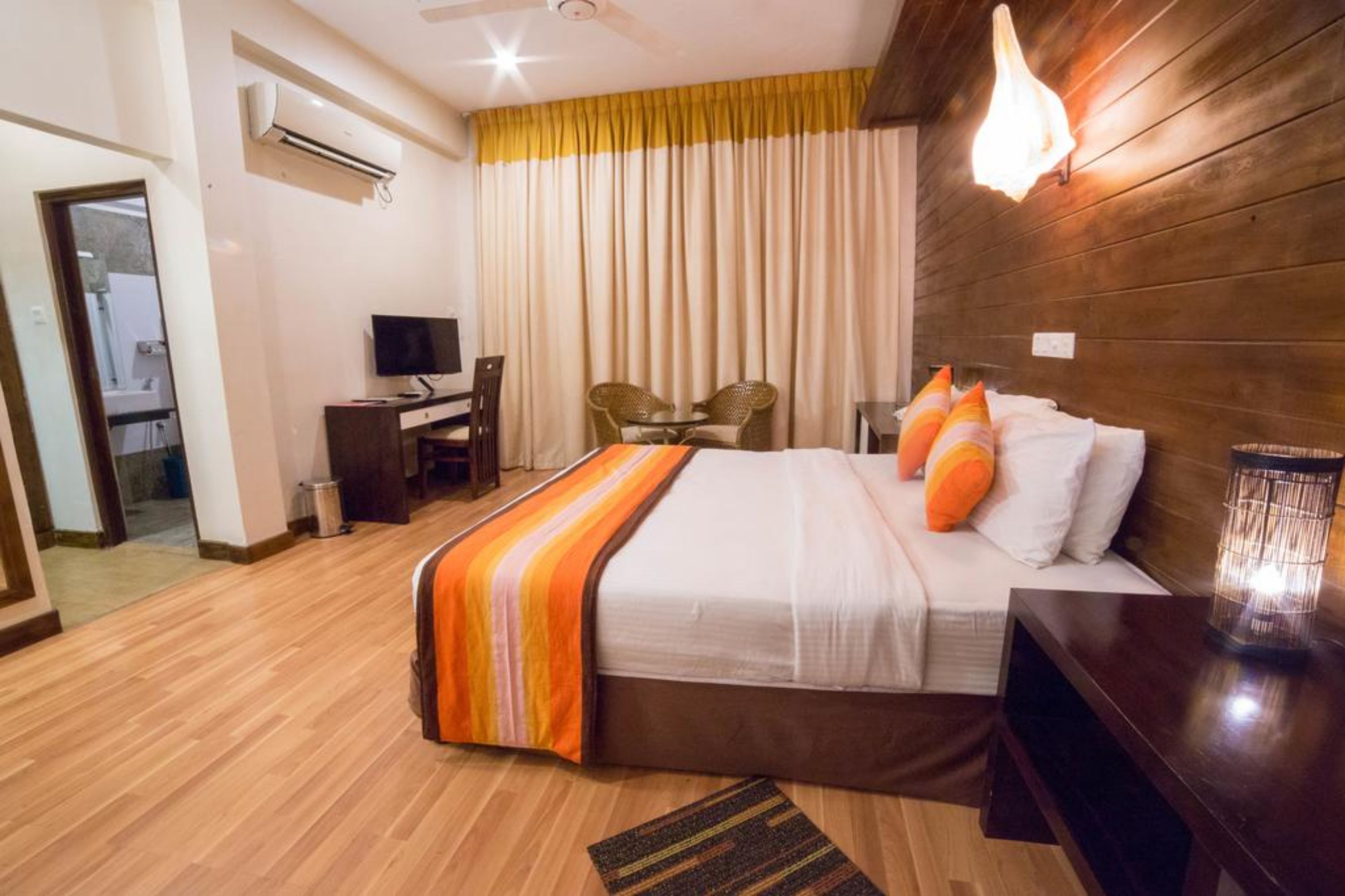 A hotel room with a large bed, a desk, a chair, and a TV.