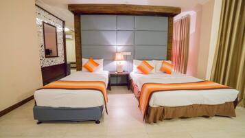 A hotel room with two beds, a nightstand with a lamp, a mirror, and a window with curtains.