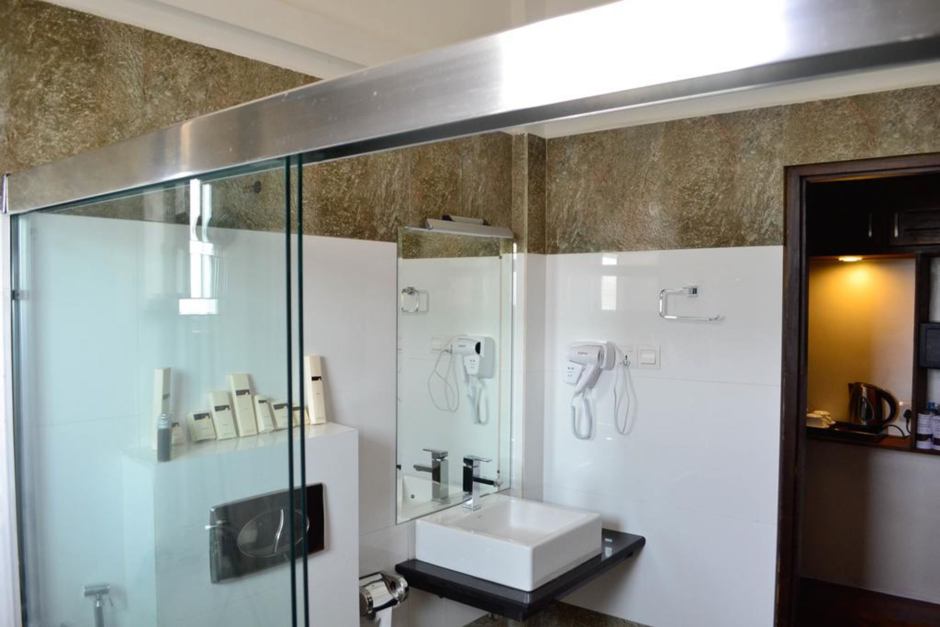 Une salle de bain moderne avec une douche à parois de verre, un lavabo blanc et un miroir au-dessus.