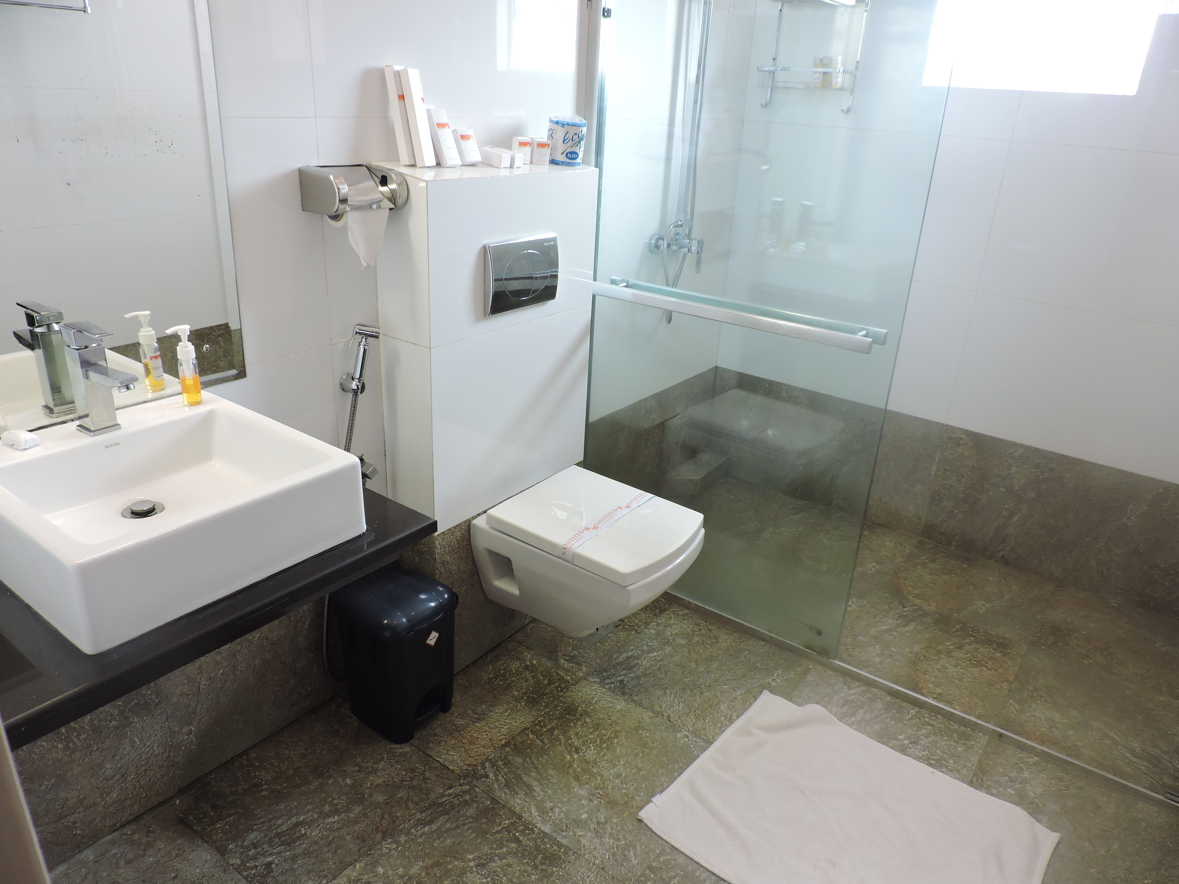 A bathroom with a white sink, toilet, and glass shower enclosure.