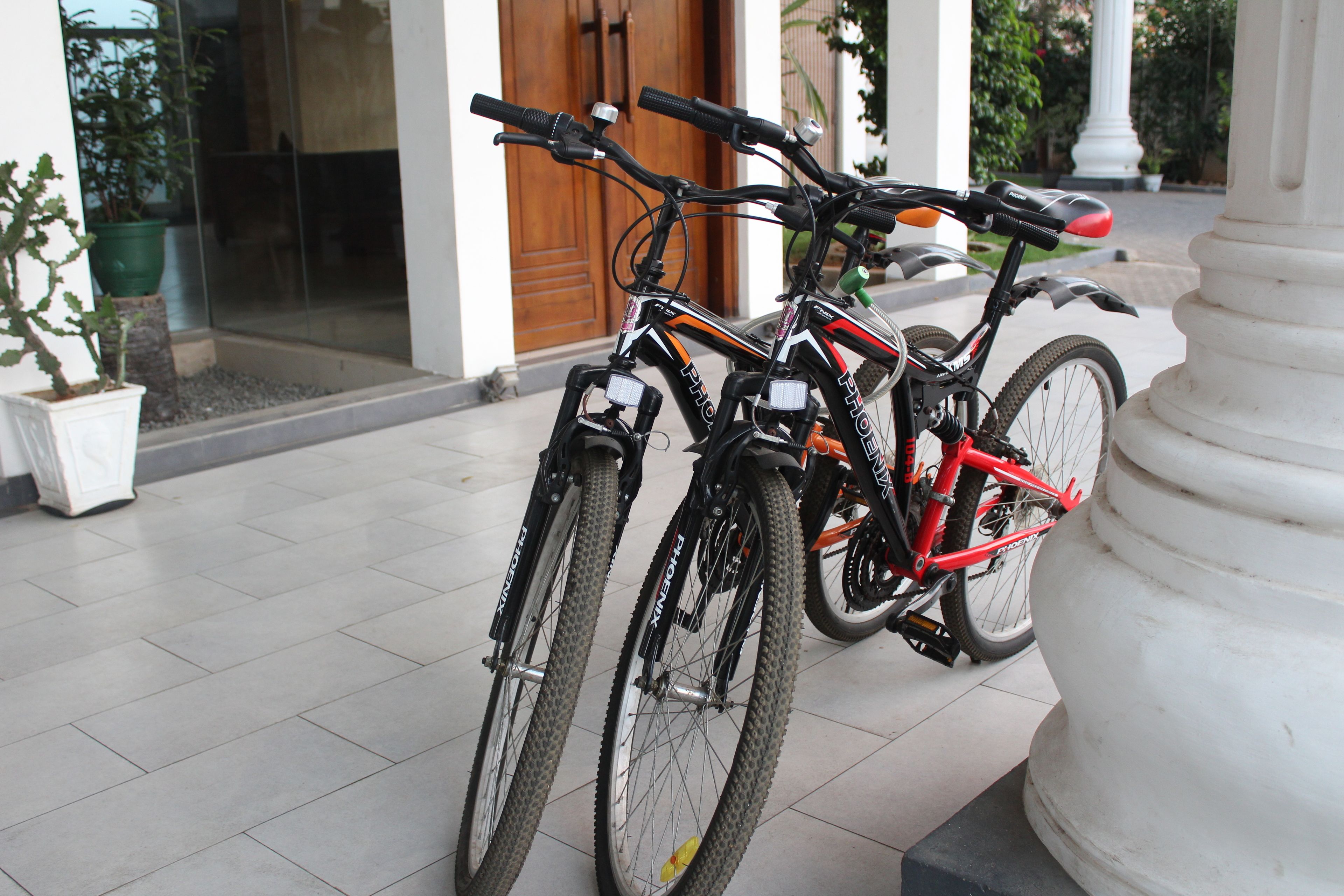 Two bicycles parked next to a white column.