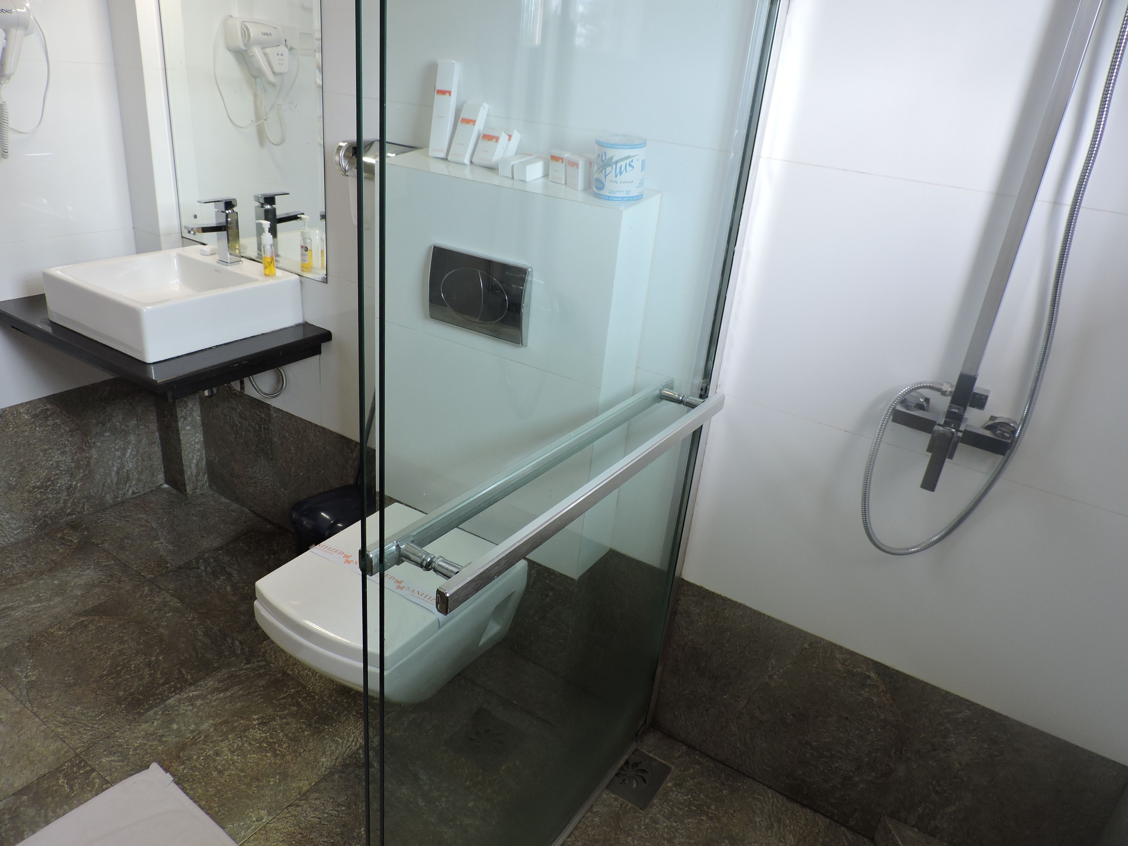 A modern bathroom with a glass-enclosed shower, a white sink, and a black countertop.