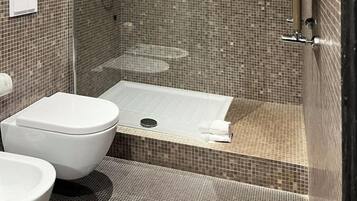 Une salle de bain moderne avec une douche à parois de verre, des toilettes blanches et une baignoire.