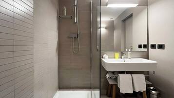 Un bagno moderno con cabina doccia in vetro, lavabo bianco e specchio.