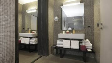 A modern bathroom with two sinks, a large mirror, and a towel rack.