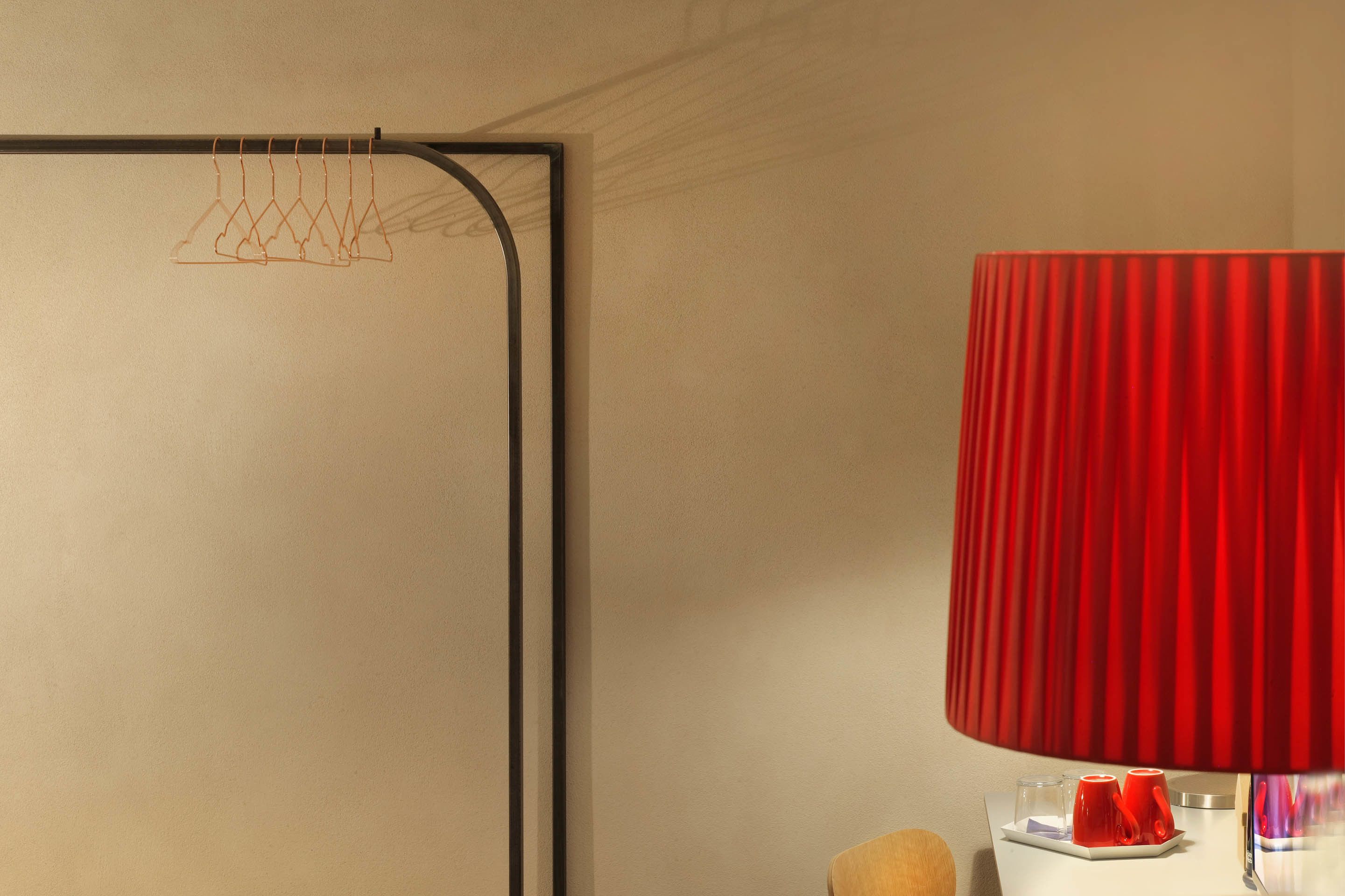 A room with a red lamp, a white table, and a wall-mounted coat rack.