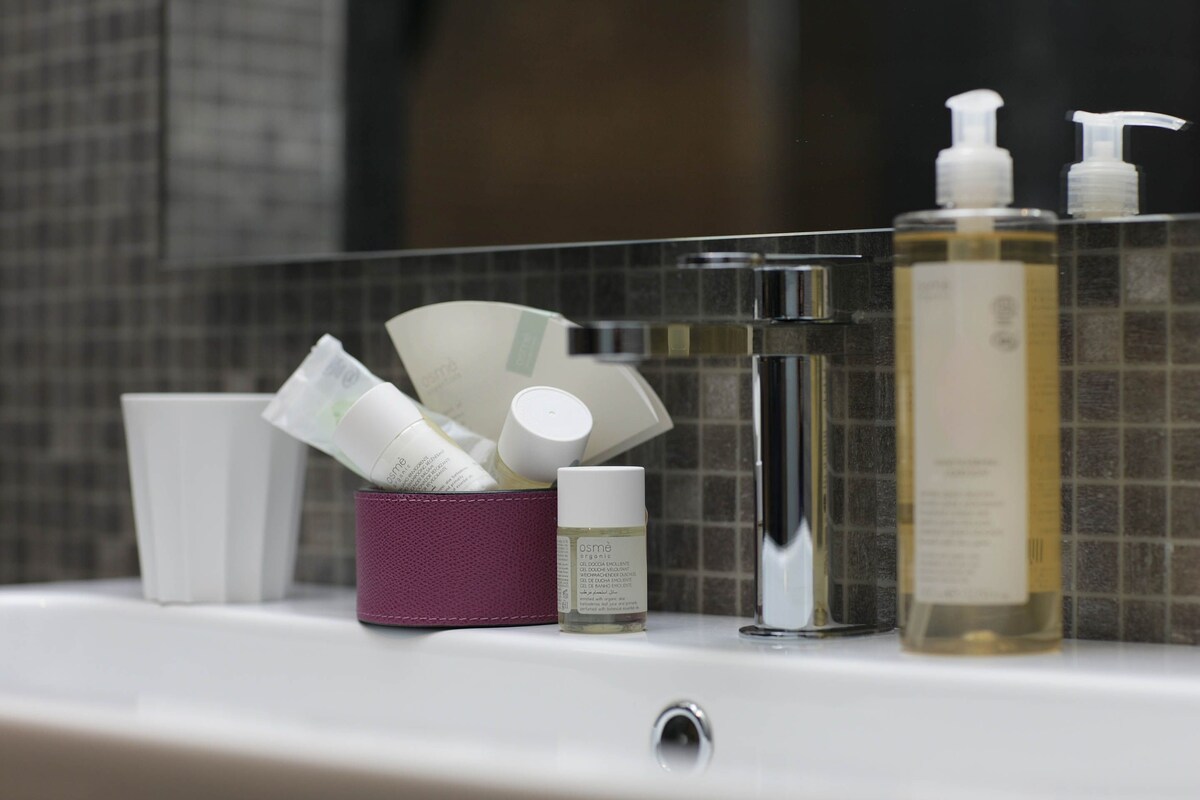 A bathroom counter with toiletries including a bottle of liquid soap, a container of cream, and a small bottle of lotion.