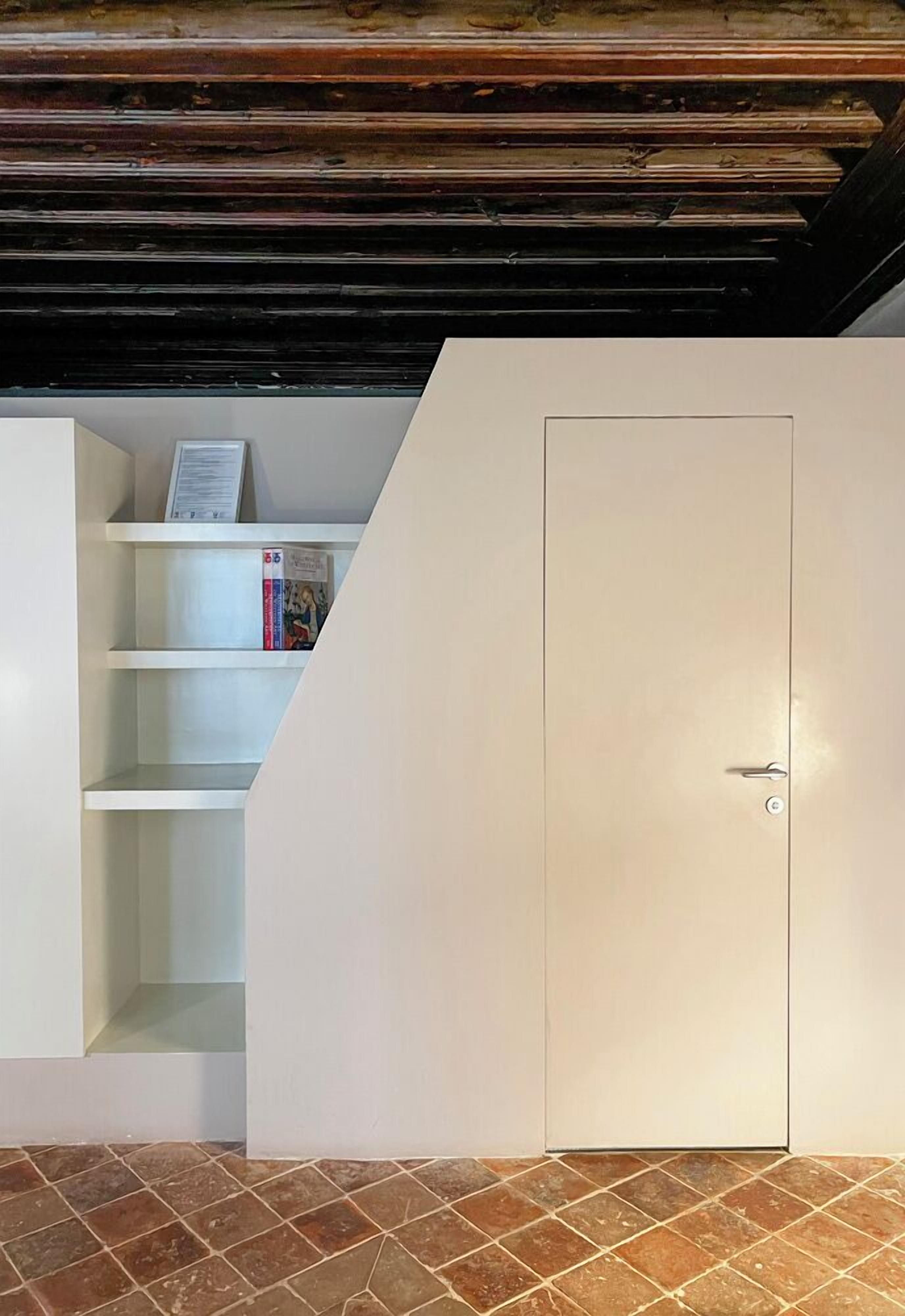 A room with a white wardrobe, a bookshelf with books, and a tiled floor.