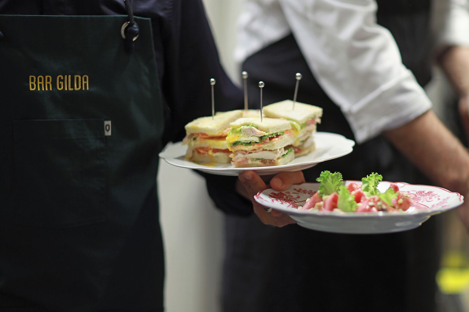 Une personne tenant une assiette avec un sandwich et une petite salade.