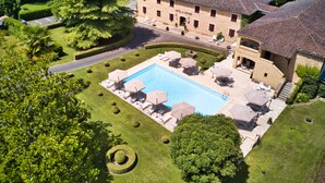 A hotel with a swimming pool, outdoor seating, and a well-maintained garden. - Hôtel des Roches (Les Eyzies)