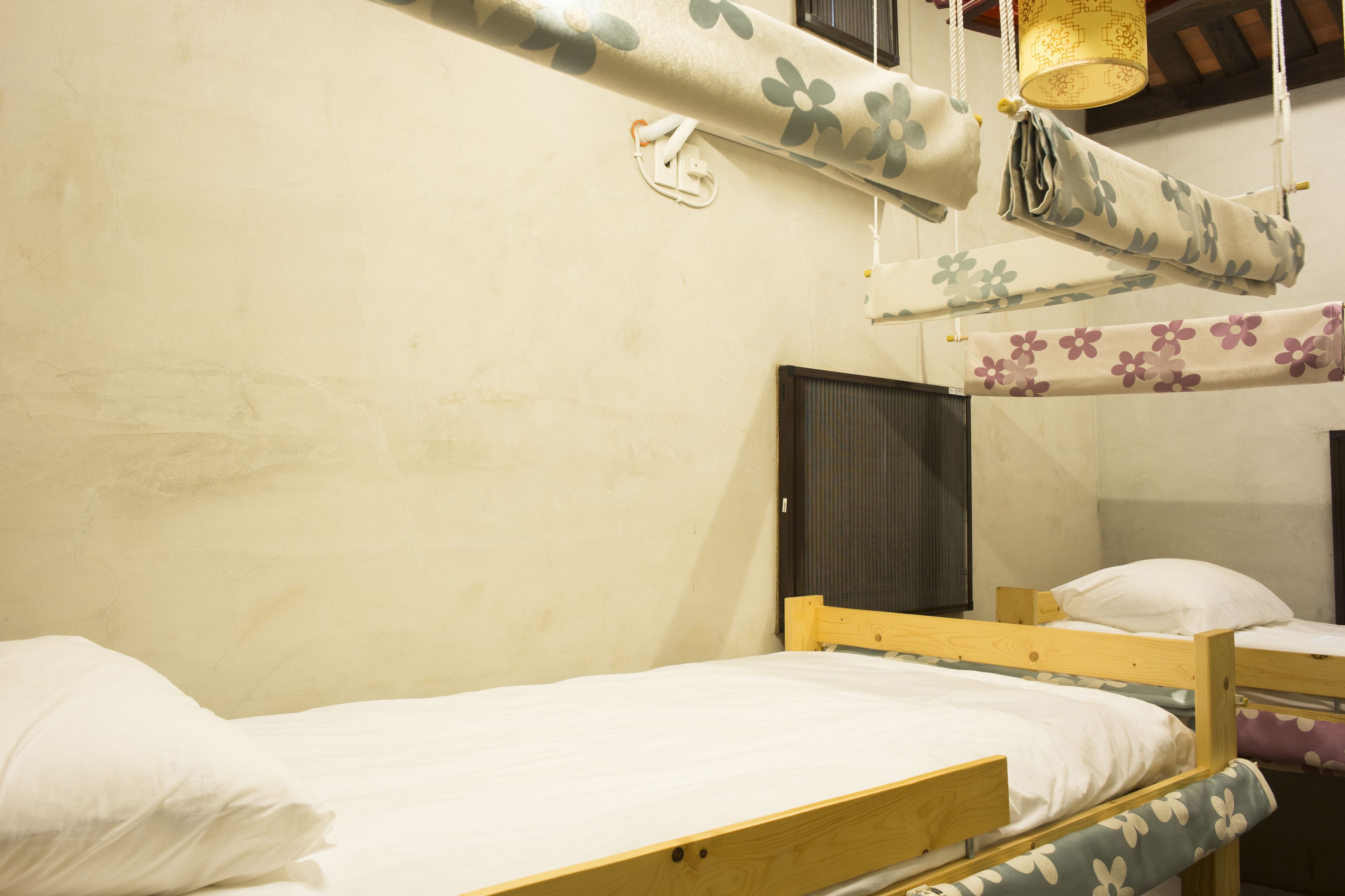 Uma cama beliche com estrutura de madeira e roupa de cama branca. Há uma pequena prateleira de madeira na cama inferior.