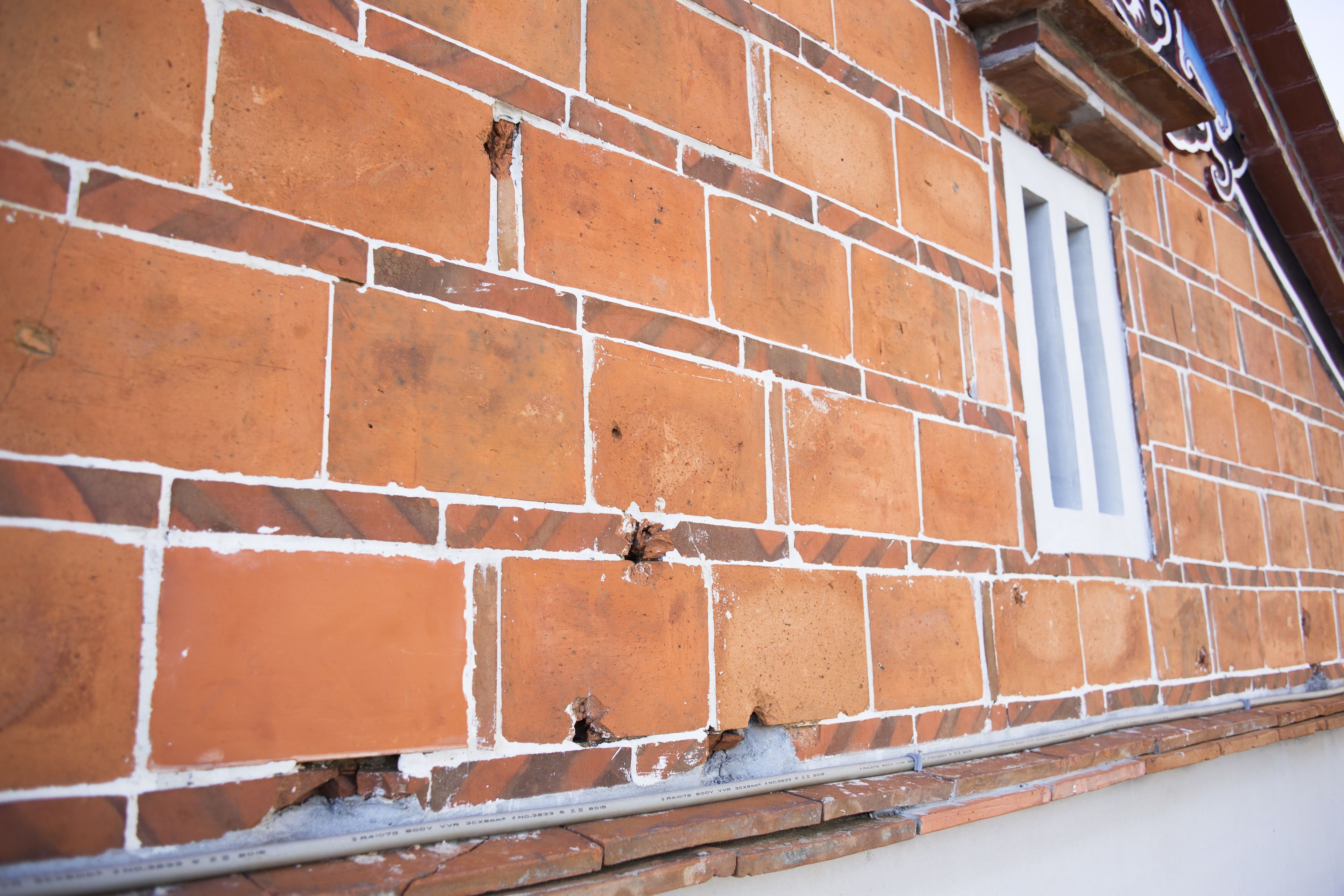A brick wall with a window and a visible pipe.