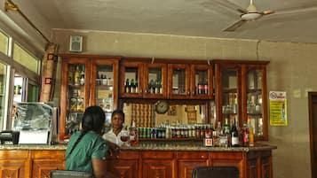 Zona de bar con armarios de madera, un reloj y varias botellas.