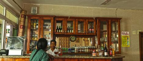 A bar area with wooden cabinets, a clock, and various bottles.
