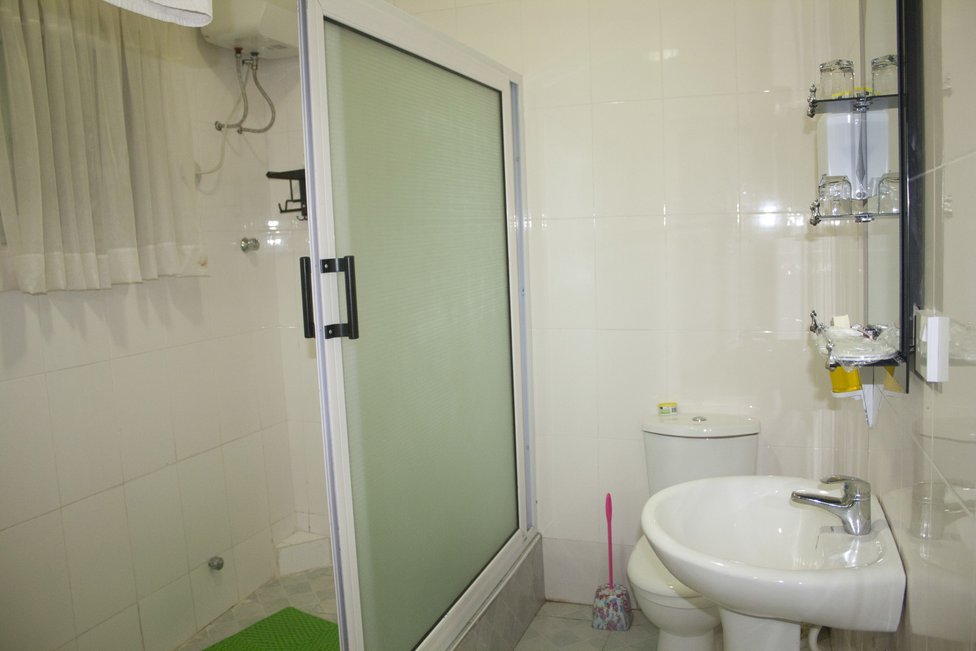 Et badeværelse med bruser, toilet og vask.