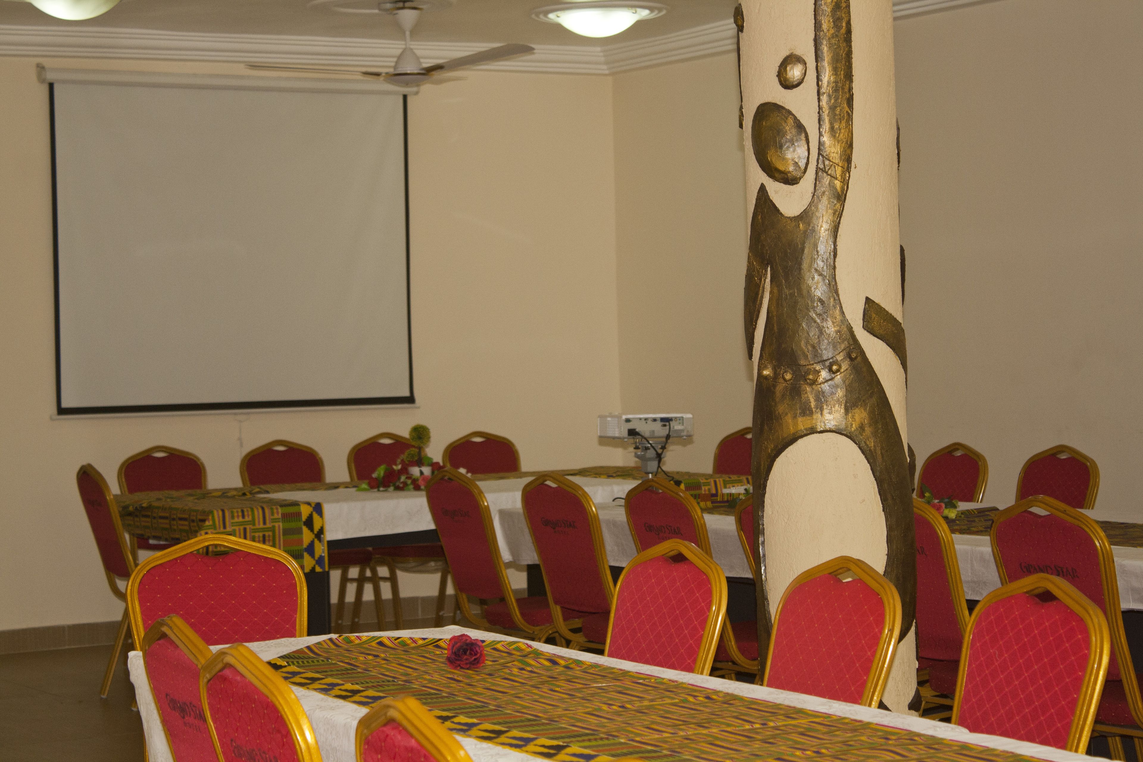 A conference room with a whiteboard, red chairs, and a table with a patterned tablecloth.